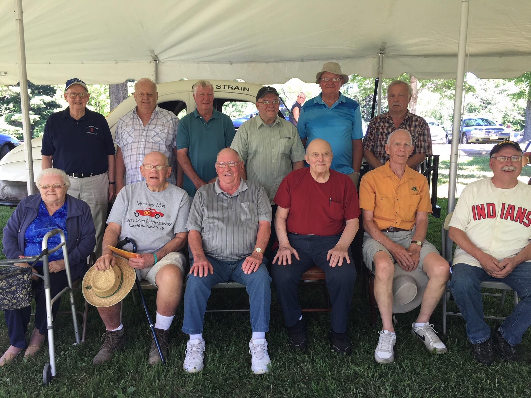 Group photo taken 7-8-18 at Ottaway Park: Back row left to right: Dave Turner (driver), Ron Blackmer (driver), Wally Howser (son of driver Jim Howser), John Swartout (son of original builder and owner of Coon Road Speedway, Joel Swartout), Skip Furlow (driver), Bill Catania (builder of #18 replica race car). Front row left to right: Emma Strain (widow of driver Don Strain), Ken See (driver), Al Brumagin (driver), Russ Weise (driver), Ray Sonnenberg (driver), Sean Hardy (current property owner of the site of
