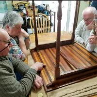 This photo shows on left, Bonnie and Dick Lancaster, and on right George and Tracy Riedesel examining the bottom of the mystery table on April 1, 2018. Photo by Val Macer